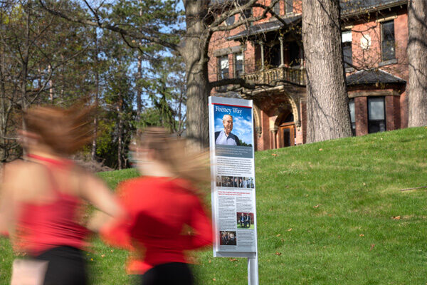 runners move by Signage at the corner of Feeney Way and Tower Road.