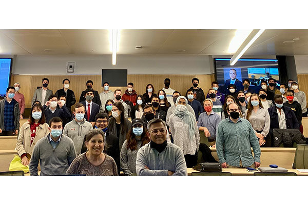 students standing up in a full lecture hall.