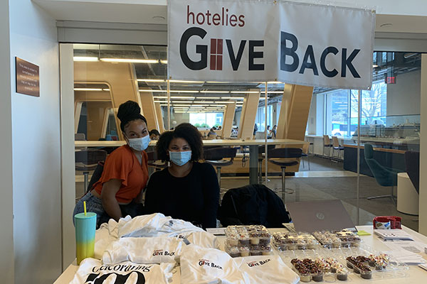 two young women seated at a table covered with T-shirts and cupcakes.