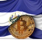 Image of a round, metal Bitcoin draped in the flag of El Salvador.