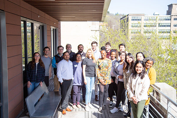 Group of students and instructors standing outside on a balcony posing for photo.