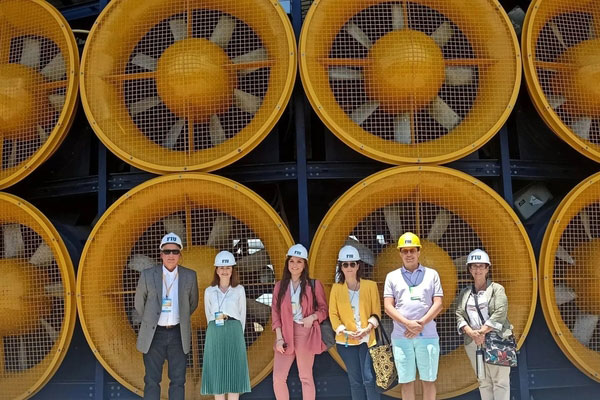 A picture of Ina Gjika and other conference attendees standing in front of large turbines.