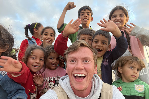 Doug Barnard, smiling wide and surrounded by smiling, laughing children.