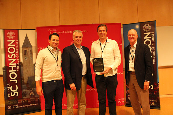 Four white men smiling. One is holding a plaque.