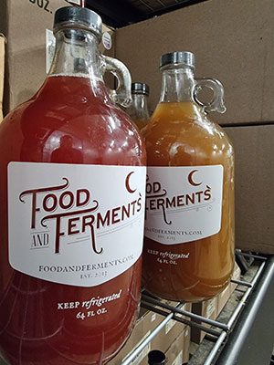 Large Jars of fermented goods on a rack.