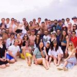 a large group of young adults on a sandy beach.
