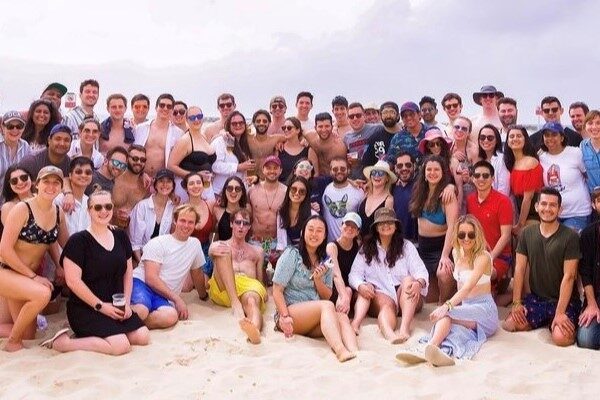 a large group of young adults on a sandy beach.