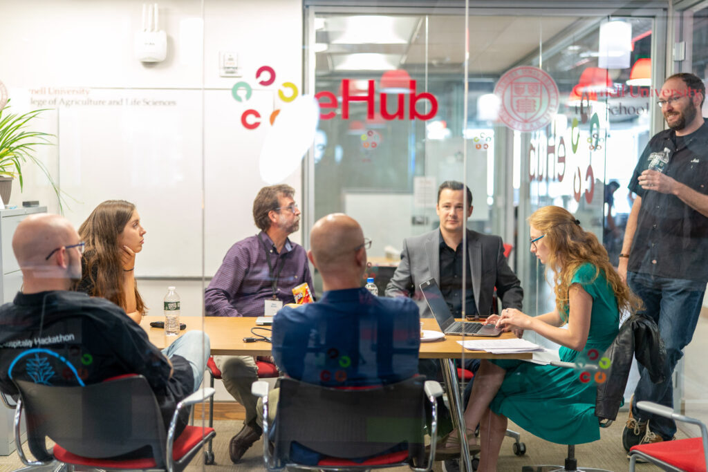 Jess Petitt '05 (standing) meets with his team of mentors during the 2019 Hilton Hospitality Hackathon.