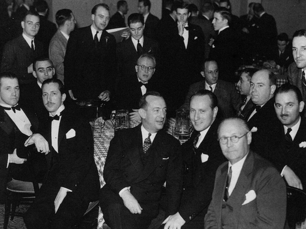 Black and white image of people in formal business attire in a lounge in New York City.