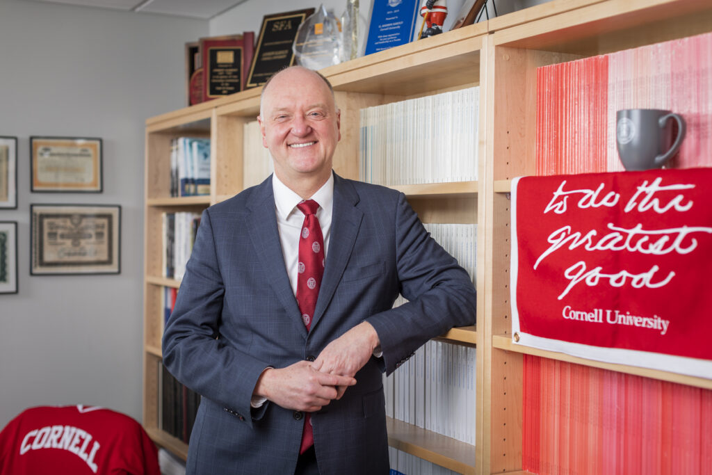 Dean Andrew Karolyi stands in front of a bookcase in his office.