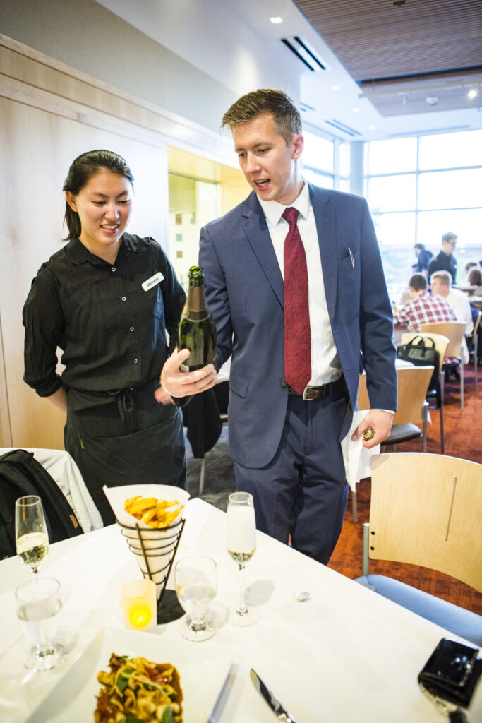 Lecturer Christopher Gaulke demonstrates for Michelle (Chuanwen) Chen ’17 the correct way to serve Champagne.