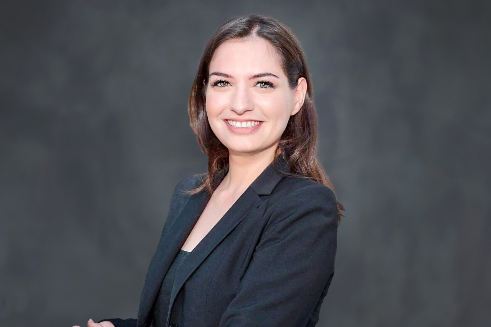 Headshot of Övül Sezer smiling in a black blazer.