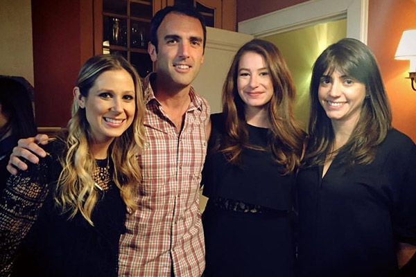 3 women and 1 man standing next to each other and smiling.