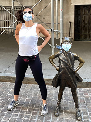 Mariam Kalandarishvili standing next to and imitating the pose of the Fearless Girl sculpture.