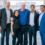 4 men and one woman standing and smiling.