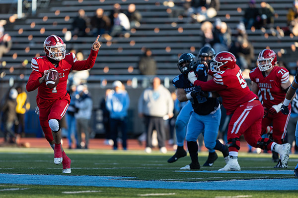 Jameson Wang running with a football while teammates fend off the opposing team.