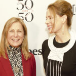 two women standing next to each other and smiling.