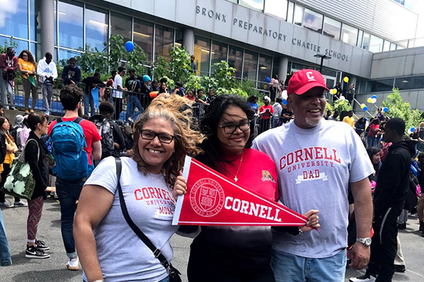 Melanie and her parents wearing Cornell T-shirts and many other students and parents in front of Bronx Preparatory Charter School.
