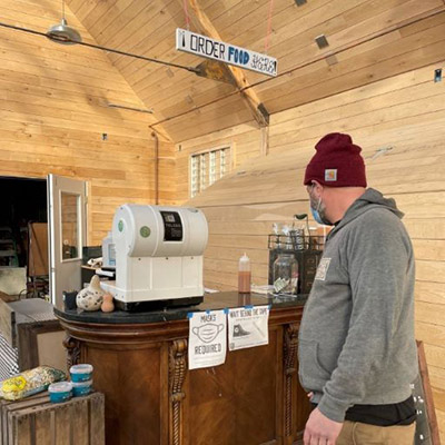 A man standing at the counter with a cash register where you order food at Stone Bend Farm.