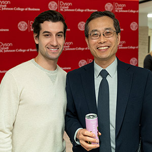 two men standing next to each other. The man on the left is holding a can of Elements Drinks.