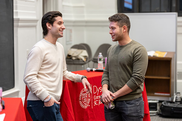 Steven Izen standing and talking with a student at the front of a lecture hall.