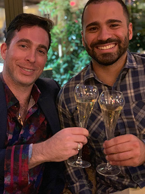two men clinking wine glasses and smiling.