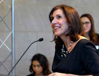 Dean Kate Walsh speaking at the podium at the Hotel Ezra Cornell cocktail reception in the Beck Center.
