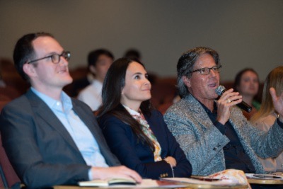 Competition judge Chris Hemmeter ’86, seated next to Zach Demuth, MMH ’16 and Gilda Perez-Alvarado ’02, speaks into a microphone.