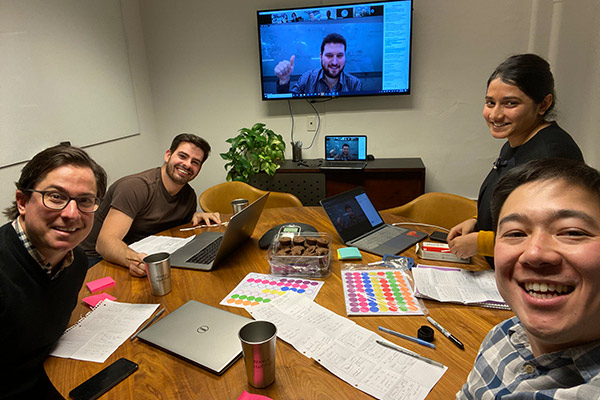 Samuel Cho working at a table with with 3 other people in a breakout room and another person on screen.