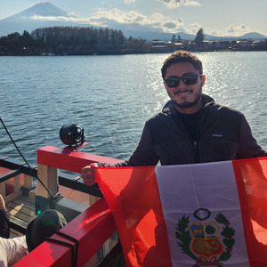 Gino Arevalo Vergara standing in front of a lake with a snow-covered mountain in the background.