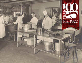 Black and white historical photo of Nolan School kitchen with chefs.
