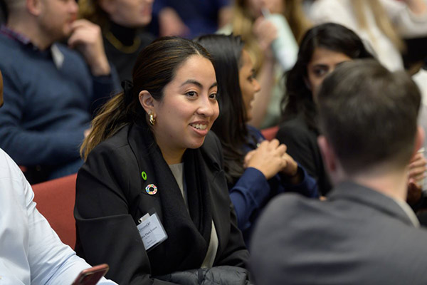 Alejandra Plaza Limon seated in an auditorium and interacting with fellow attendees.