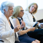 3 women sitting side by side with one speaking and gesturing.