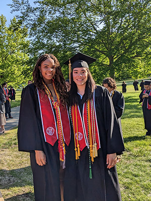 Two women in graduation caps and gowns on the Cornell Arts Quad.