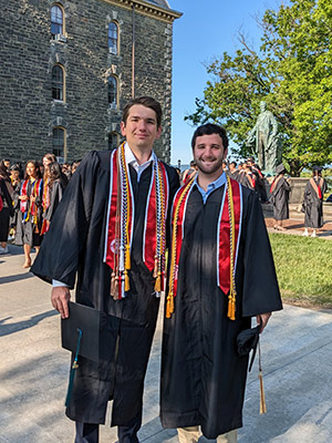  2 men in graduation caps and gowns on Cornell’s Arts Quad.