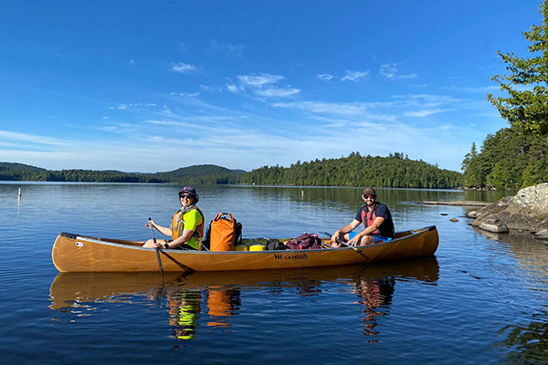 two people in a canoe on a lake surrounded by trees.