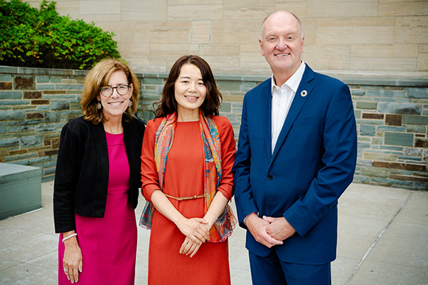 two women and one man, dressed in professional attire, standing side by side and smiling.