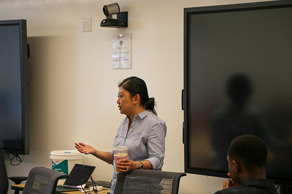 a woman stands in a conference room and speaks.