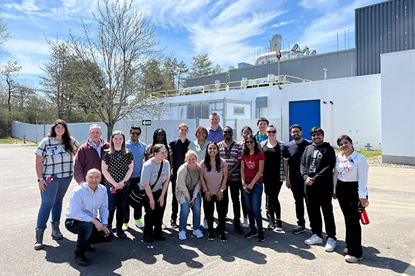 Vishal Gaur and about 20 students outside a manufacturing facility on a sunny spring day.