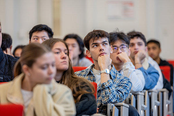 Students sitting in a lecture hall and listening.