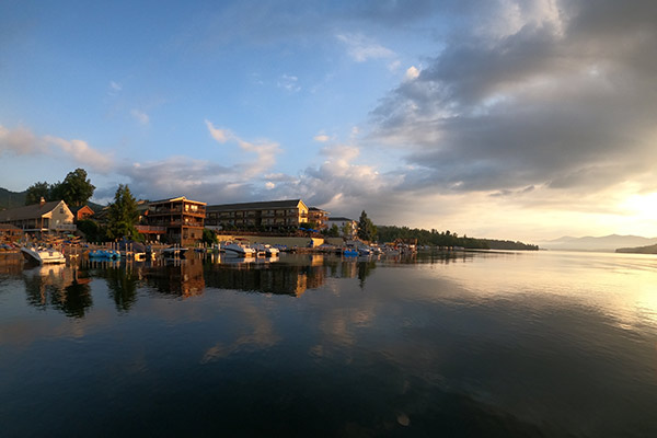 Evening photo of Lake George and buildings on the waterfront with blue sky and a few high clouds in the background.