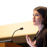 a headshot of Maxine Bédat speaking into a microphone.