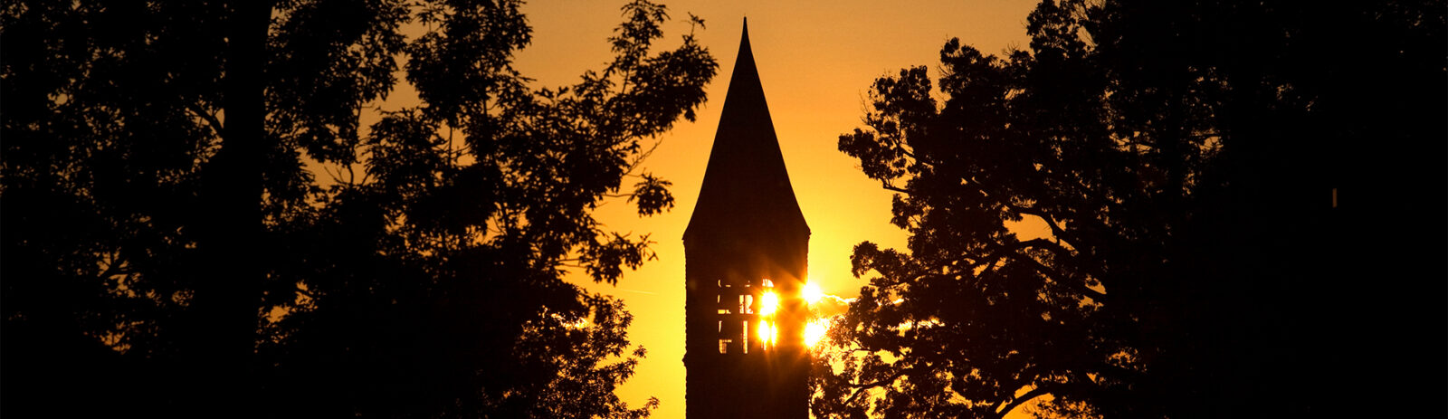 McGraw Tower with the sun setting behind it.