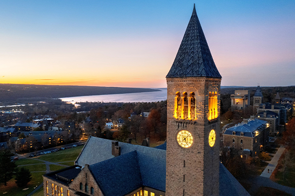 McGraw Tower lit up at sunset with a lake visible in the background.