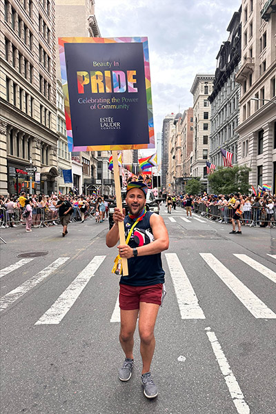Christian Balmaseda-Lucca walking in a parade in the middle of the street in NYC and carrying a "Beauty in Pride" sign.