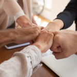 photo of five different people's fists joined together in a fist bump.
