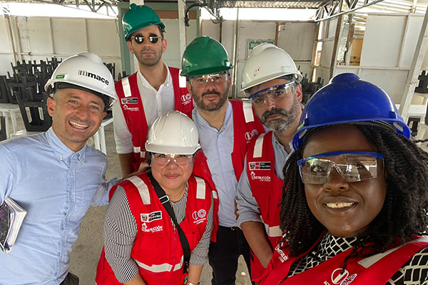 Two women and four men wearing hardhats posing for a selfie photo in a partially completed room.