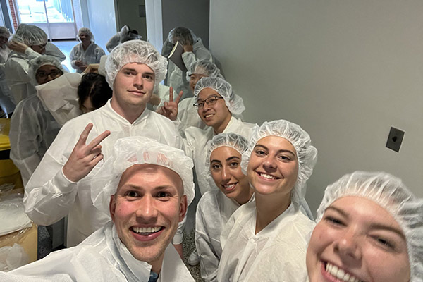 Ian Cairns and a group of interns wearing white coats and white hairnets.