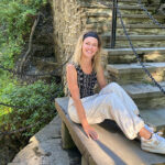 Kyra Stiggelbout sitting on a stone step wearing New Balance sneakers.