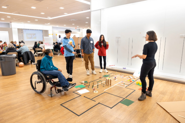 Image of five individuals collaborating over a proposed layout on the floor.